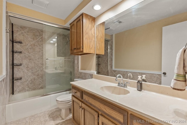 full bathroom featuring vanity, toilet, combined bath / shower with glass door, and tile patterned floors