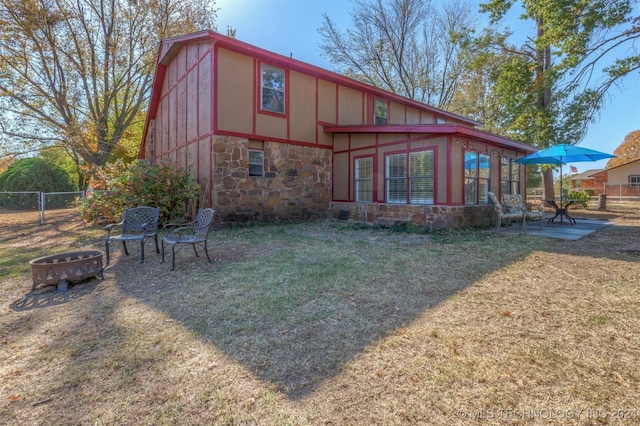 back of property with a patio, an outdoor fire pit, a yard, and a sunroom