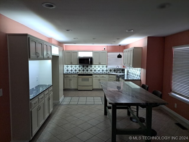 kitchen featuring sink, backsplash, hanging light fixtures, light tile patterned flooring, and electric range