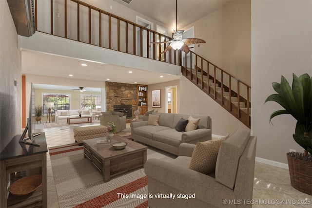 tiled living room featuring ceiling fan, a high ceiling, and a fireplace