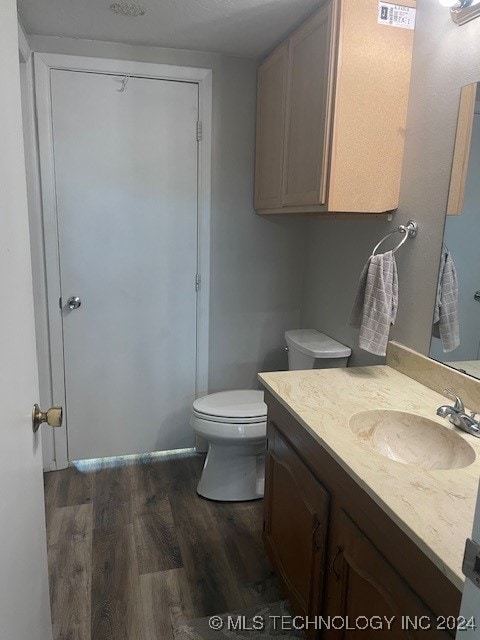 bathroom featuring wood-type flooring, vanity, and toilet