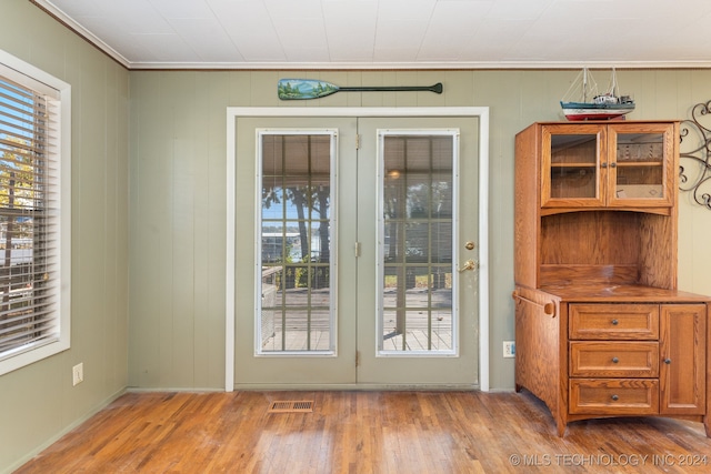 doorway to outside featuring french doors, wood-type flooring, crown molding, and plenty of natural light