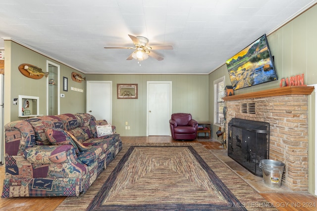 living room with light hardwood / wood-style flooring, crown molding, ceiling fan, and a brick fireplace