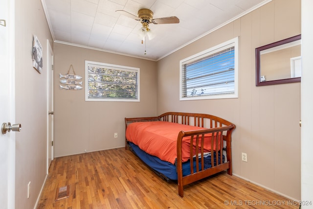 bedroom featuring light hardwood / wood-style floors, ceiling fan, and crown molding