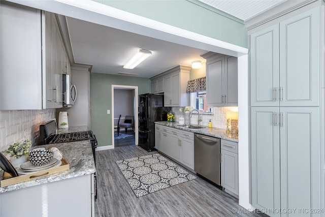 kitchen featuring appliances with stainless steel finishes, sink, backsplash, gray cabinets, and light hardwood / wood-style flooring