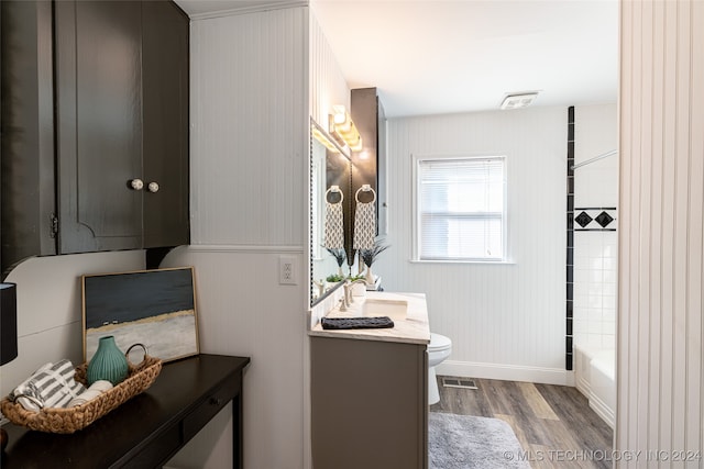 full bathroom with toilet, hardwood / wood-style floors, tiled shower / bath combo, and vanity