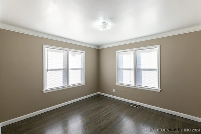 empty room with dark wood-type flooring, crown molding, and plenty of natural light