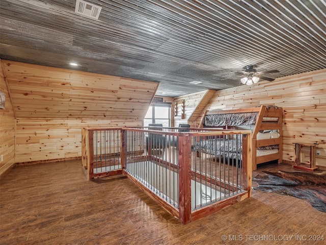 additional living space with ceiling fan, hardwood / wood-style flooring, and wooden walls