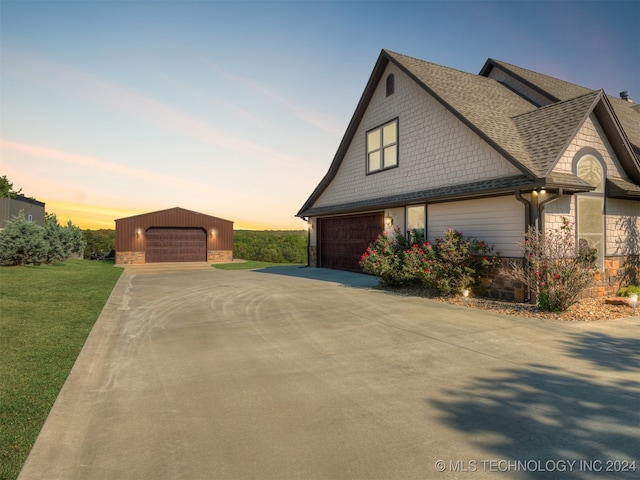 property exterior at dusk with a yard, an outbuilding, and a garage