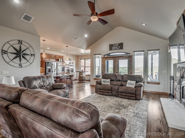 living room with a fireplace, dark hardwood / wood-style flooring, plenty of natural light, and ceiling fan with notable chandelier