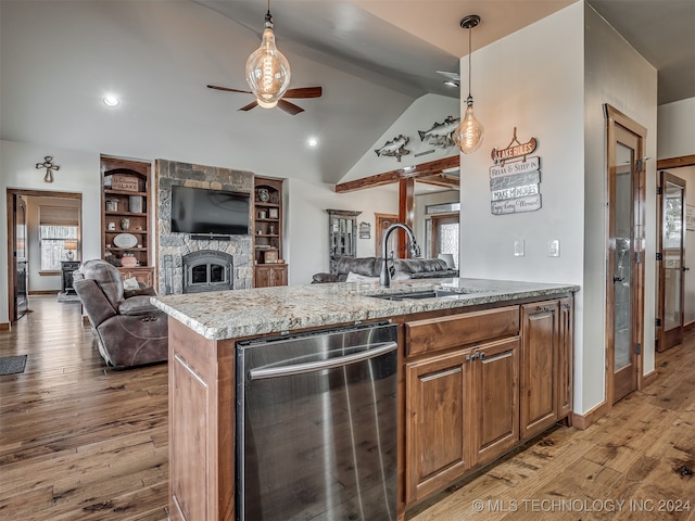 kitchen with a stone fireplace, sink, vaulted ceiling, pendant lighting, and light hardwood / wood-style floors