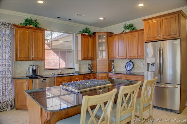 kitchen featuring a kitchen island, stainless steel appliances, sink, crown molding, and a breakfast bar area