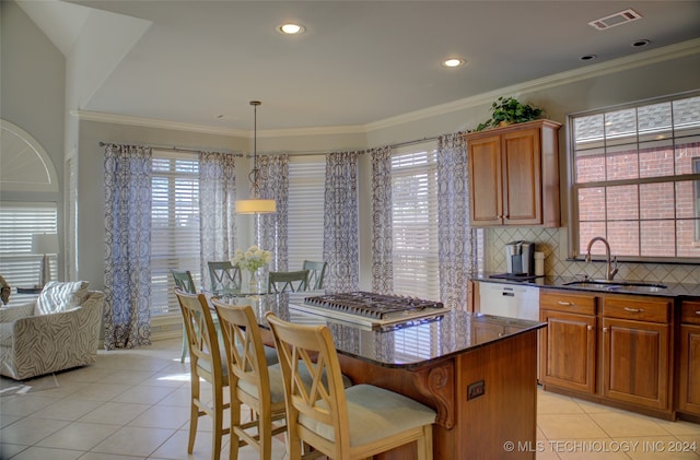 kitchen featuring light tile patterned floors, decorative light fixtures, dark stone countertops, a breakfast bar, and sink