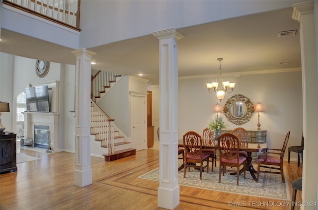 dining area featuring ornamental molding, ornate columns, a notable chandelier, and light wood-type flooring