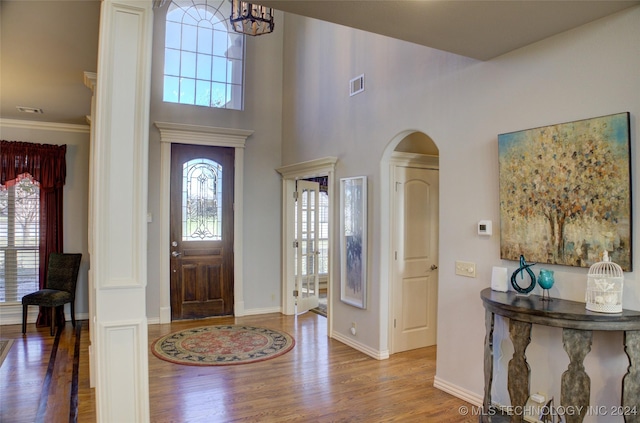 foyer entrance featuring an inviting chandelier, crown molding, and wood-type flooring