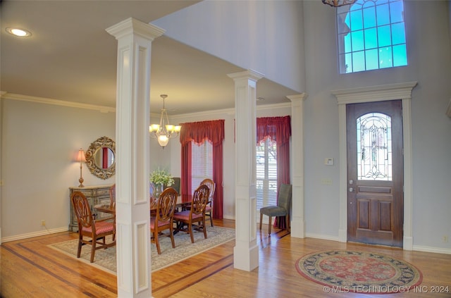 entrance foyer with ornate columns, ornamental molding, hardwood / wood-style floors, and an inviting chandelier