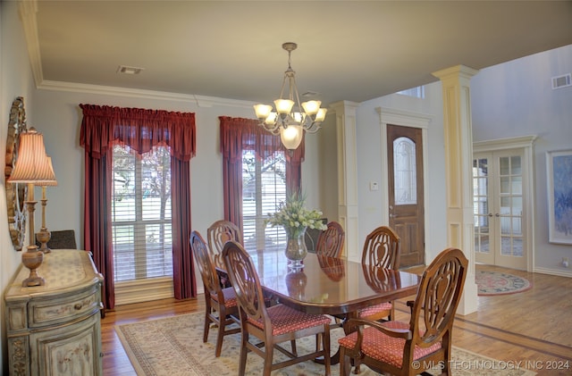 dining area with a notable chandelier, ornamental molding, wood-type flooring, and decorative columns