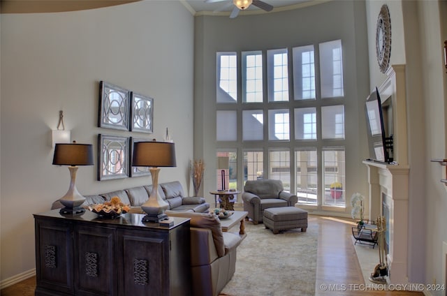 living room with ceiling fan, ornamental molding, and a towering ceiling