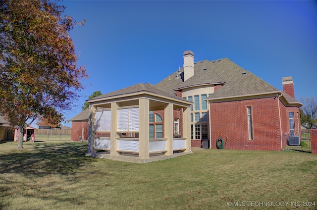 back of property featuring central air condition unit and a yard