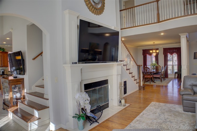 living room with an inviting chandelier, crown molding, light hardwood / wood-style floors, and a high ceiling