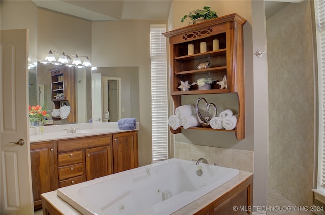 bathroom featuring a relaxing tiled tub and vanity