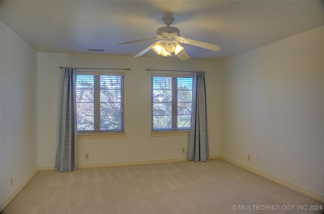 empty room with ceiling fan, light colored carpet, and plenty of natural light