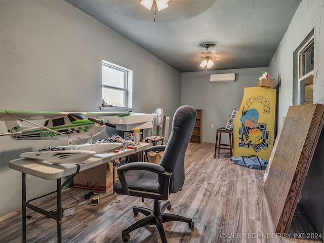 office area featuring a wall unit AC, wood-type flooring, and ceiling fan