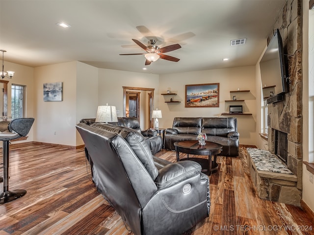 living room featuring hardwood / wood-style floors, a fireplace, and ceiling fan with notable chandelier