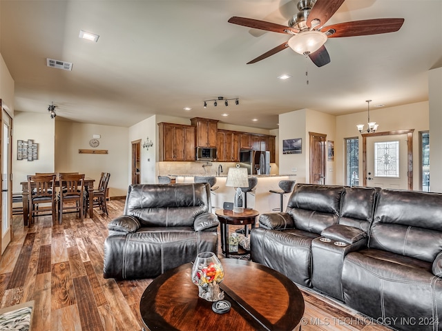 living room featuring hardwood / wood-style flooring and ceiling fan with notable chandelier