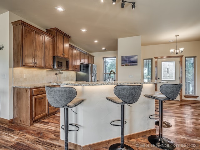 kitchen with plenty of natural light, stainless steel appliances, dark wood-type flooring, and a kitchen bar