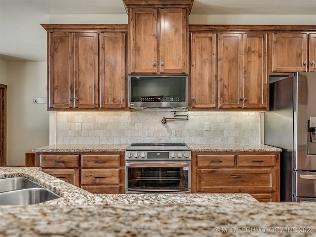 kitchen featuring appliances with stainless steel finishes, light stone counters, and backsplash