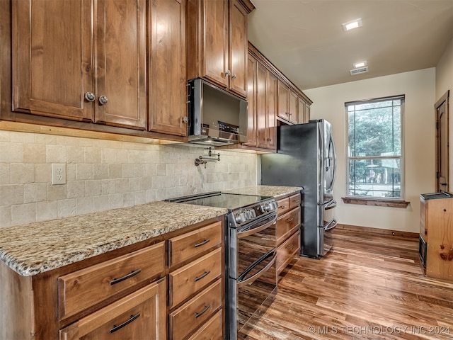 kitchen with appliances with stainless steel finishes, decorative backsplash, light stone counters, and dark hardwood / wood-style flooring