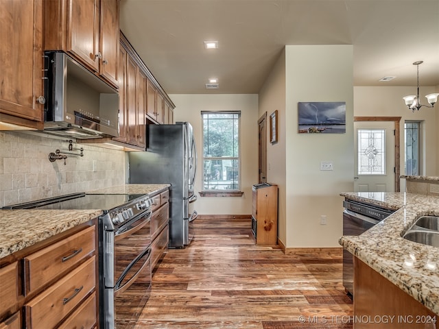 kitchen with dark hardwood / wood-style floors, a healthy amount of sunlight, stainless steel appliances, and hanging light fixtures