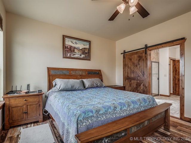 bedroom featuring a barn door, wood-type flooring, and ceiling fan