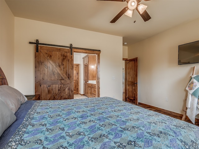 unfurnished bedroom featuring a barn door, ensuite bath, and ceiling fan