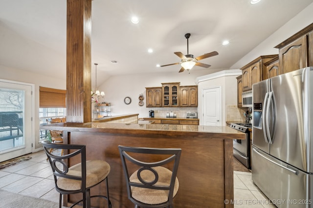 kitchen with light tile patterned floors, stainless steel appliances, kitchen peninsula, and a breakfast bar