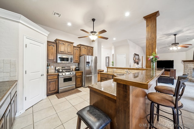 kitchen featuring a breakfast bar, appliances with stainless steel finishes, backsplash, a kitchen island, and light tile patterned flooring