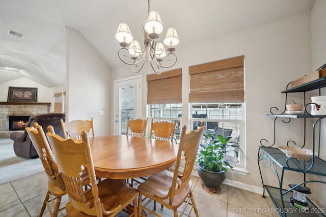 tiled dining area with lofted ceiling, a notable chandelier, and a fireplace