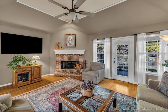 living room with vaulted ceiling, hardwood / wood-style flooring, a brick fireplace, and ceiling fan