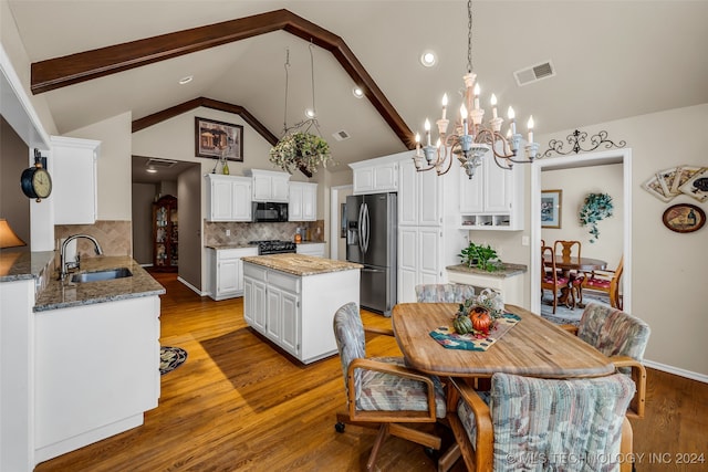 kitchen with white cabinetry, sink, a center island, decorative backsplash, and black appliances