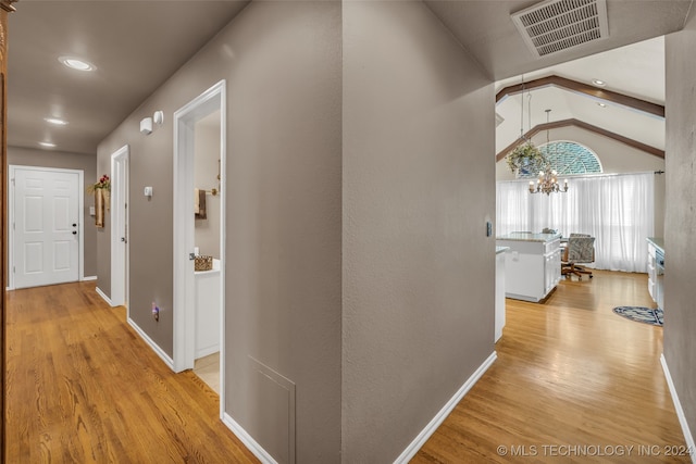 hallway featuring a chandelier, light wood-type flooring, and lofted ceiling with beams