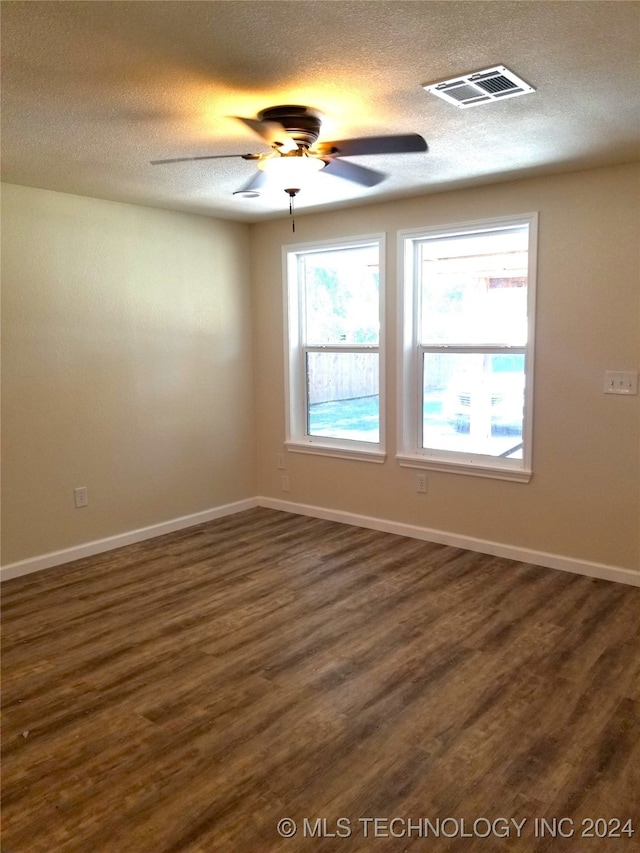 spare room with a textured ceiling, dark wood-type flooring, and ceiling fan