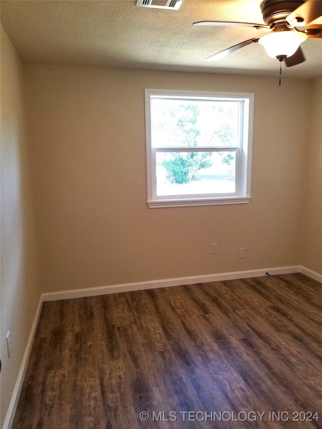 empty room with a textured ceiling, ceiling fan, and dark hardwood / wood-style flooring