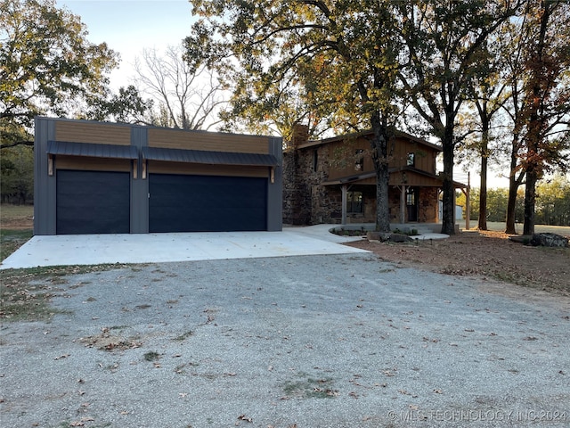 view of front facade with stone siding, a chimney, and gravel driveway