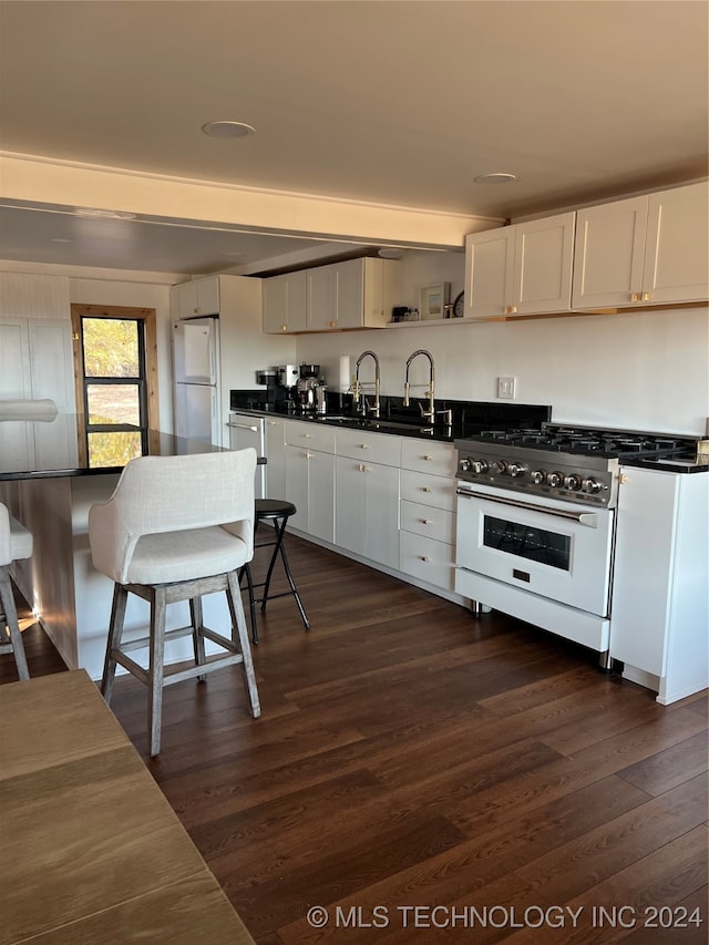 kitchen with gas range, dark countertops, dark wood-style floors, and freestanding refrigerator