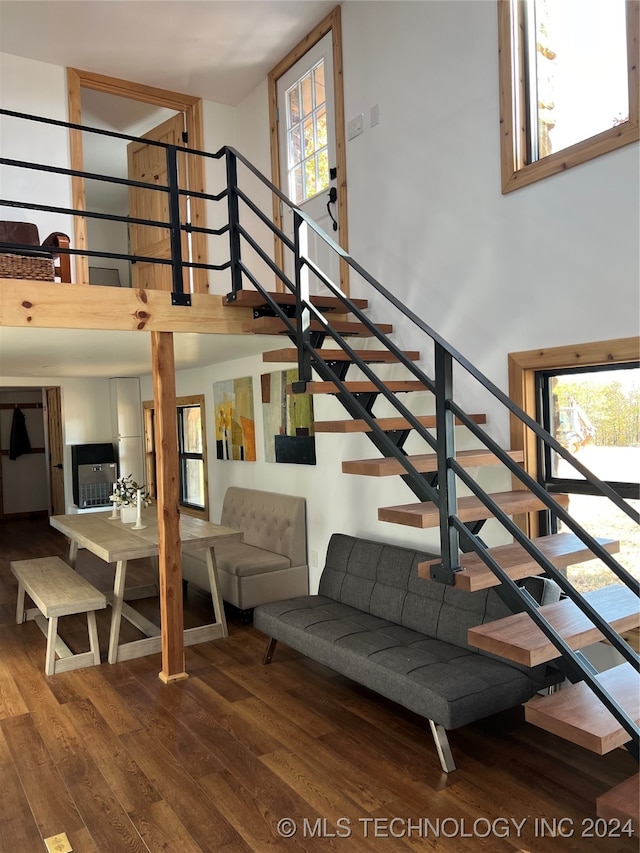 stairway with a towering ceiling and wood finished floors