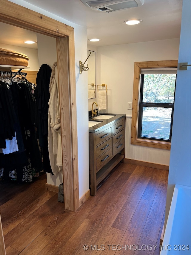 full bath featuring vanity, a walk in closet, wood finished floors, and baseboards