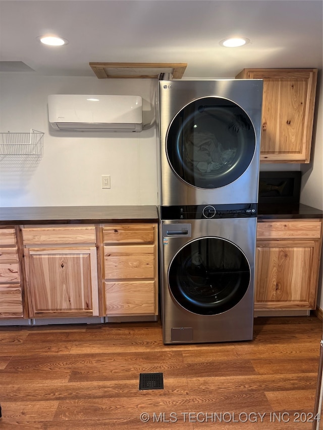 washroom with dark wood-type flooring, stacked washer / drying machine, and cabinets