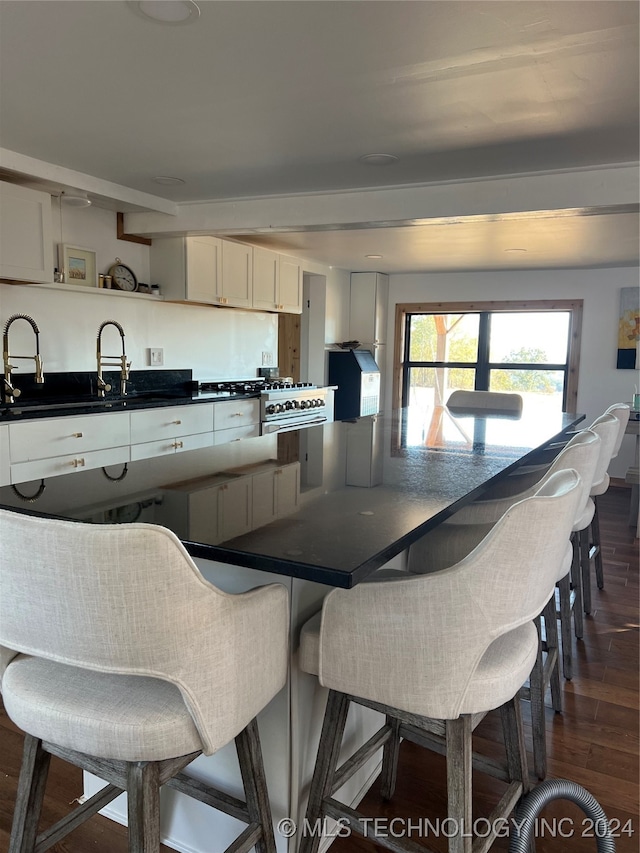 kitchen with dark countertops, dark wood-type flooring, a kitchen breakfast bar, white cabinets, and open shelves