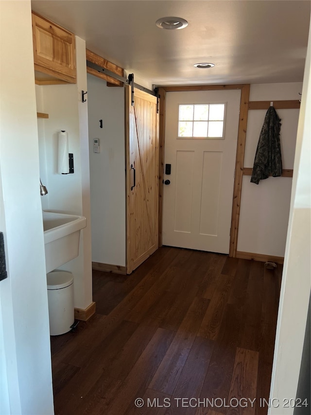 doorway featuring baseboards, dark wood-type flooring, and a barn door